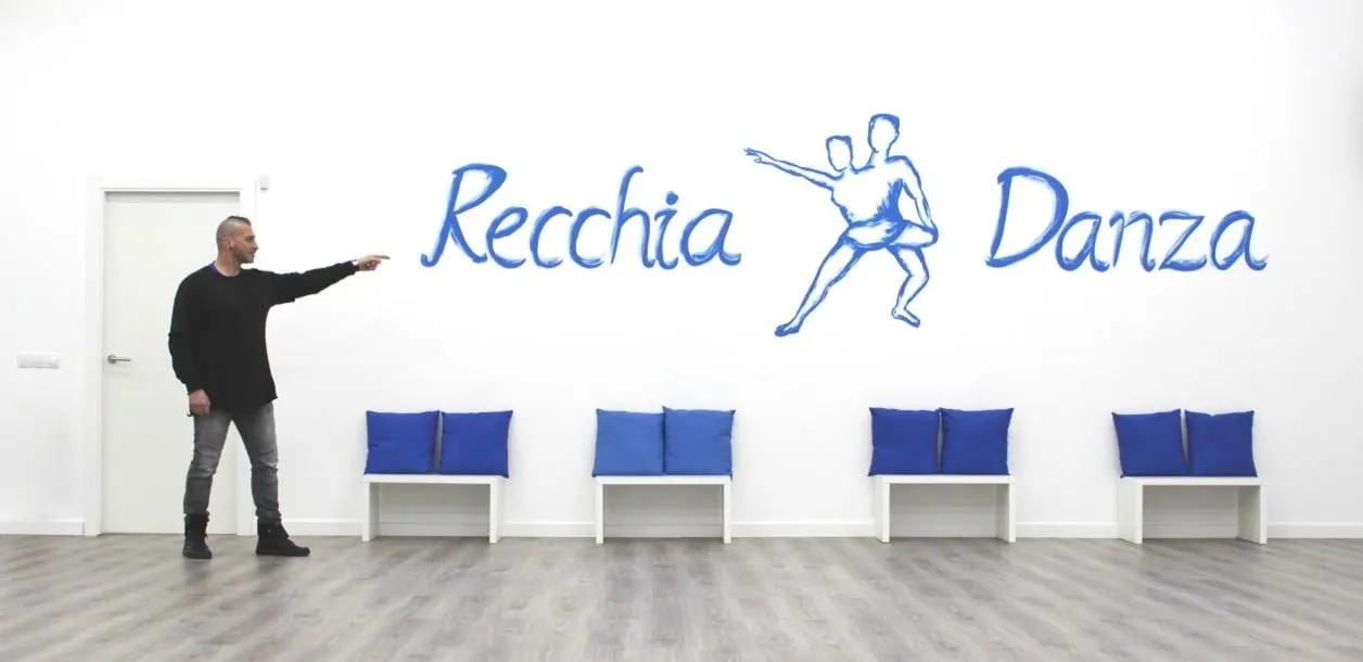 Lorenzo señalando el mural de RecchiaDanza en la sala de baile